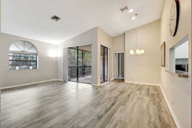 5450 Verona Dr Unit L, Boynton Beach, FL 33437 - empty room with vaulted ceiling, a chandelier, healthy amount of natural light, light wood-style flooring, and a textured ceiling