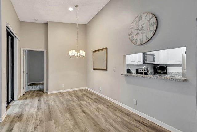 5450 Verona Dr Unit L, Boynton Beach, FL 33437 - unfurnished dining area featuring a high ceiling, a chandelier, baseboards, and light wood finished floors