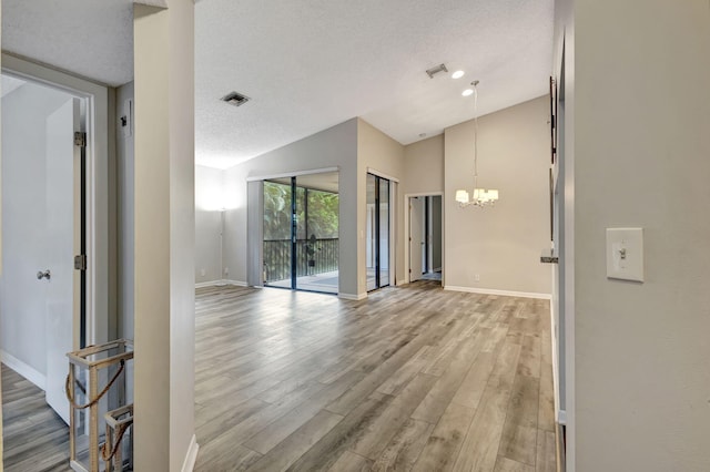 5450 Verona Dr Unit L, Boynton Beach, FL 33437 - empty room featuring wood finished floors, a chandelier, baseboards, a textured ceiling, and lofted ceiling