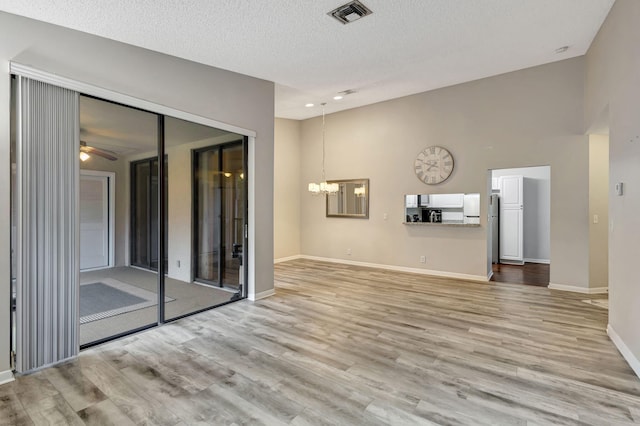 5450 Verona Dr Unit L, Boynton Beach, FL 33437 - unfurnished living room with light wood finished floors, a chandelier, baseboards, ceiling fan, and a textured ceiling