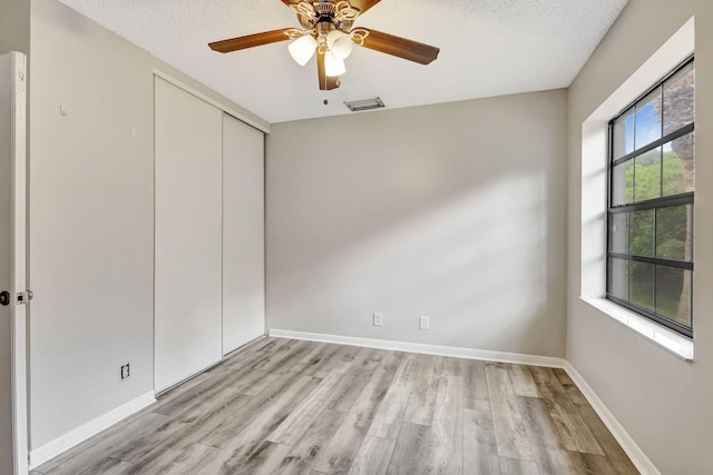 5450 Verona Dr Unit L, Boynton Beach, FL 33437 - unfurnished bedroom with light wood finished floors, a closet, baseboards, a textured ceiling, and a ceiling fan