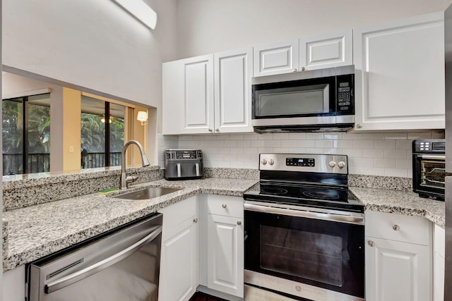 5450 Verona Dr Unit L, Boynton Beach, FL 33437 - kitchen featuring stainless steel appliances, a sink, white cabinetry, tasteful backsplash, and a towering ceiling