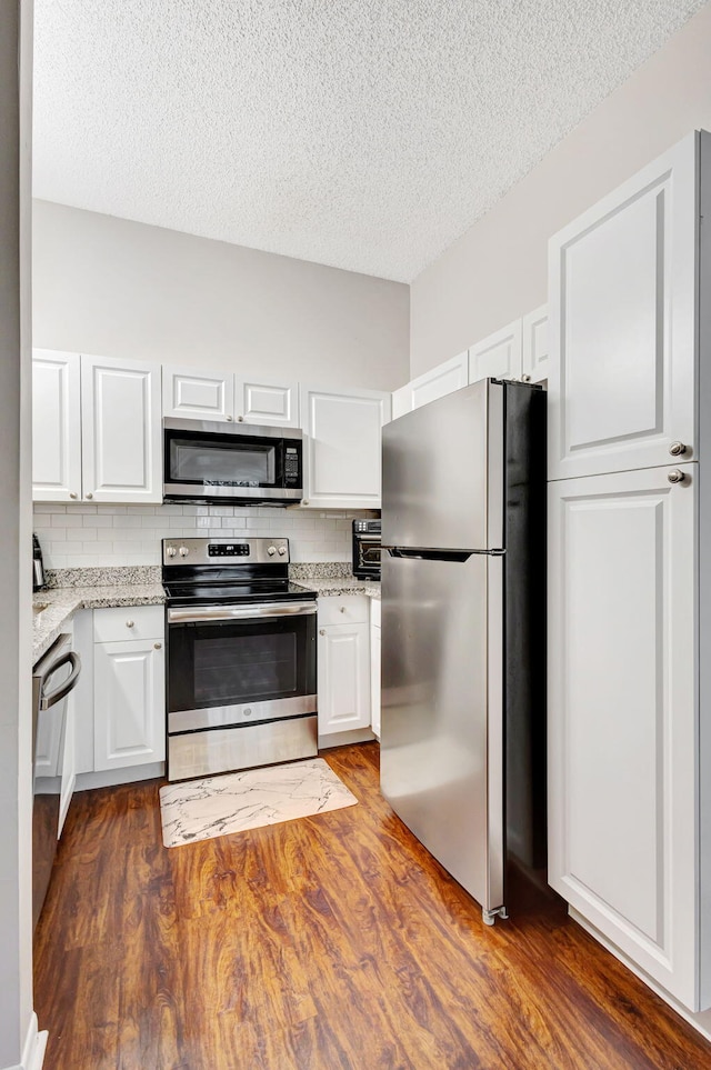 5450 Verona Dr Unit L, Boynton Beach, FL 33437 - kitchen with appliances with stainless steel finishes, white cabinetry, light stone counters, dark wood finished floors, and a textured ceiling