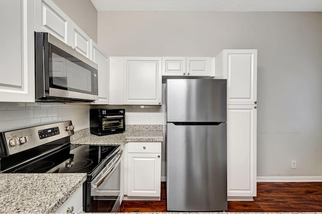 5450 Verona Dr Unit L, Boynton Beach, FL 33437 - kitchen with appliances with stainless steel finishes, decorative backsplash, white cabinets, dark wood finished floors, and light stone countertops