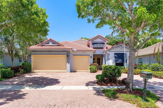 473 Cottagewood Ln, West Palm Beach, FL 33411 - view of front of home featuring an attached garage, decorative driveway, a tiled roof, and stucco siding