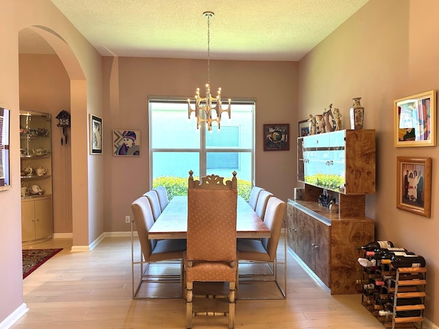473 Cottagewood Ln, West Palm Beach, FL 33411 - dining area featuring light wood-type flooring, arched walkways, a chandelier, a textured ceiling, and baseboards