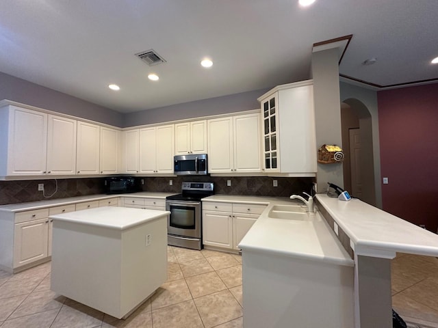 473 Cottagewood Ln, West Palm Beach, FL 33411 - kitchen featuring stainless steel appliances, a sink, arched walkways, a peninsula, and decorative backsplash
