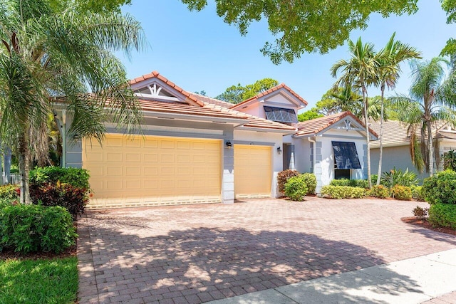 473 Cottagewood Ln, West Palm Beach, FL 33411 - view of front of house featuring driveway, an attached garage, stucco siding, and a tiled roof