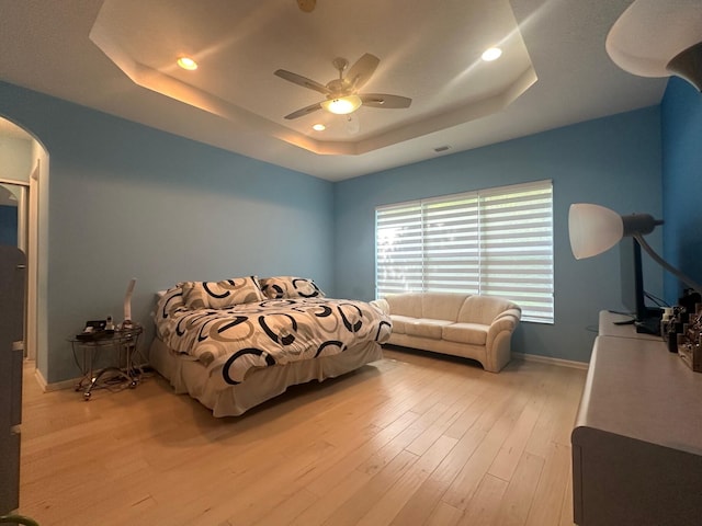 473 Cottagewood Ln, West Palm Beach, FL 33411 - bedroom with a raised ceiling, arched walkways, baseboards, light wood finished floors, and ceiling fan
