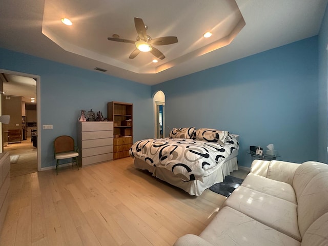 473 Cottagewood Ln, West Palm Beach, FL 33411 - bedroom featuring a raised ceiling, light wood-style flooring, recessed lighting, arched walkways, and ceiling fan