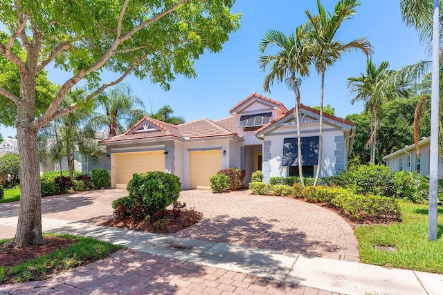473 Cottagewood Ln, West Palm Beach, FL 33411 - view of front of property featuring a tiled roof, decorative driveway, stucco siding, and a garage