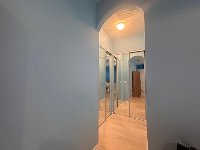 473 Cottagewood Ln, West Palm Beach, FL 33411 - corridor featuring arched walkways, light wood-style floors, and a textured ceiling