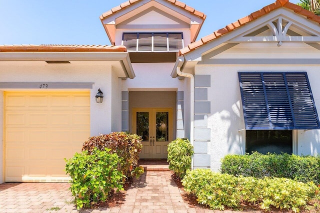 473 Cottagewood Ln, West Palm Beach, FL 33411 - view of exterior entry featuring french doors, stucco siding, an attached garage, and a tiled roof