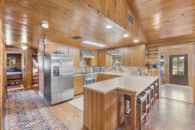 32801 US Highway 441 N Unit 64, Okeechobee, FL 34972 - kitchen with appliances with stainless steel finishes, light wood finished floors, wood ceiling, a peninsula, and wall chimney exhaust hood
