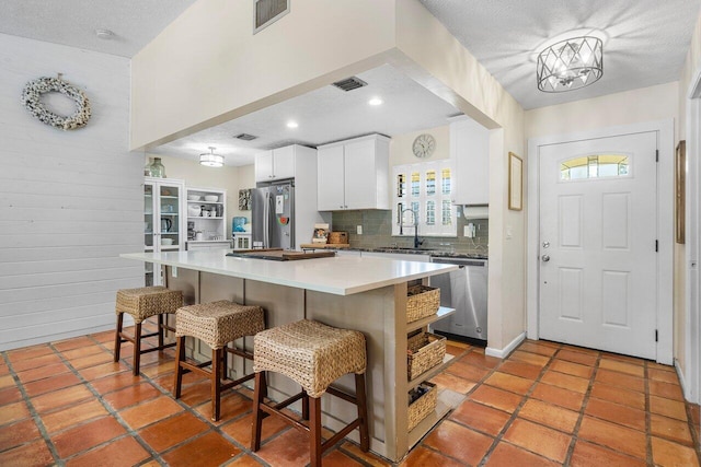 903 Oak Cir, Jupiter, FL 33458 - kitchen featuring appliances with stainless steel finishes, a kitchen breakfast bar, backsplash, white cabinetry, and a center island