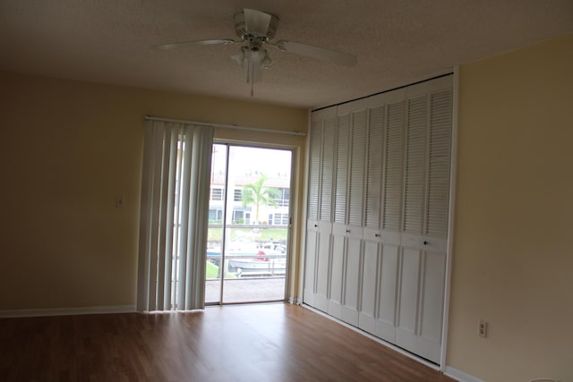 unfurnished bedroom featuring a textured ceiling, wood finished floors, access to exterior, baseboards, and ceiling fan