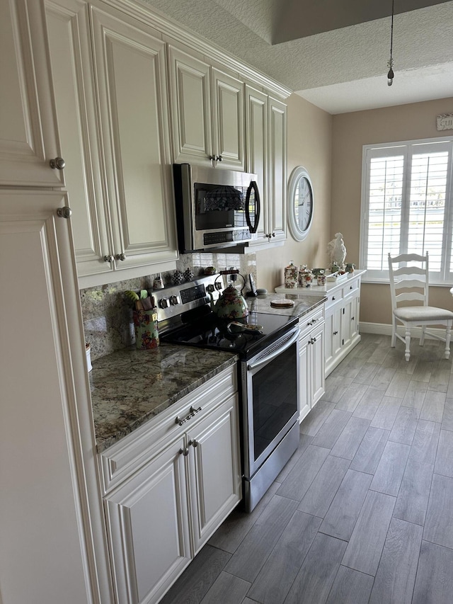 17287 Boca Club 1 Blvd Unit 1, Boca Raton, FL 33487 - kitchen featuring stainless steel appliances, light wood-type flooring, a textured ceiling, decorative backsplash, and dark stone countertops