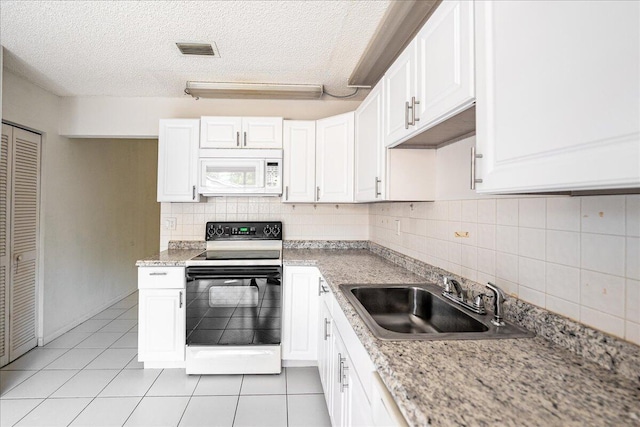 kitchen featuring white microwave, range with electric stovetop, a sink, white cabinetry, and a textured ceiling