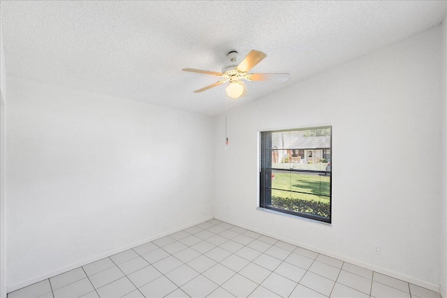 empty room with a textured ceiling, ceiling fan, baseboards, and light tile patterned floors