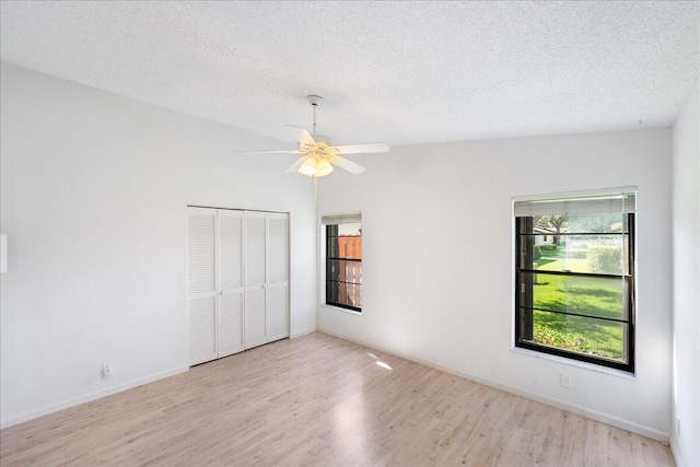 unfurnished bedroom featuring wood finished floors, a closet, a textured ceiling, a ceiling fan, and baseboards