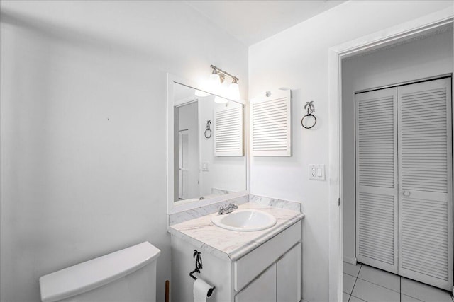 half bath featuring toilet, tile patterned floors, a closet, and vanity