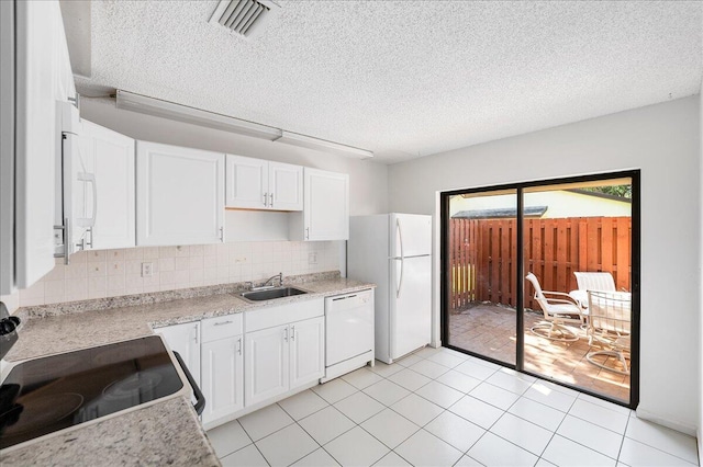 kitchen with white appliances, a sink, white cabinetry, a textured ceiling, and backsplash