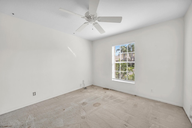 spare room with light colored carpet, ceiling fan, and baseboards