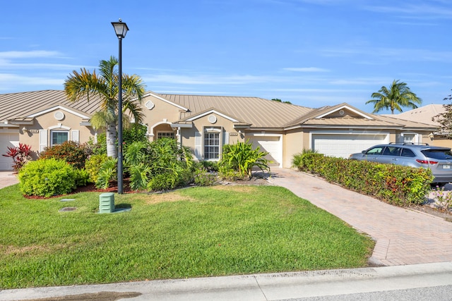 ranch-style home featuring an attached garage, stucco siding, a front yard, driveway, and metal roof