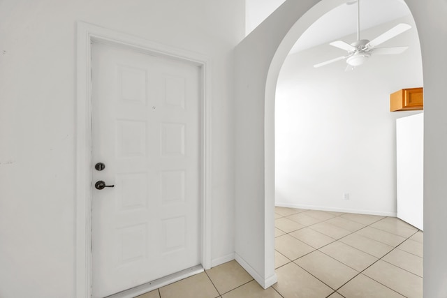 foyer with arched walkways, ceiling fan, light tile patterned flooring, and baseboards