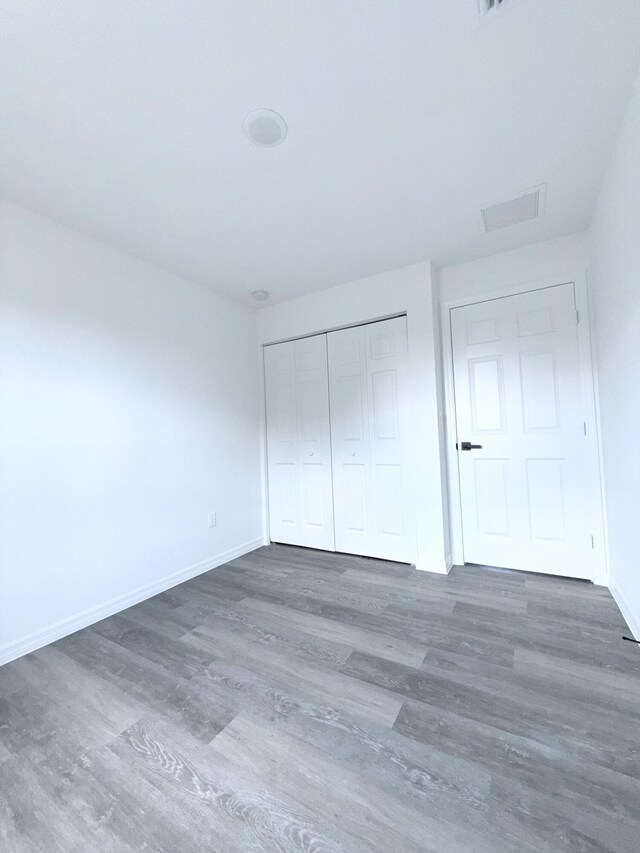 382 Mcarthur Blvd, Lehigh Acres, FL 33974 - unfurnished bedroom featuring wood finished floors, baseboards, and a closet