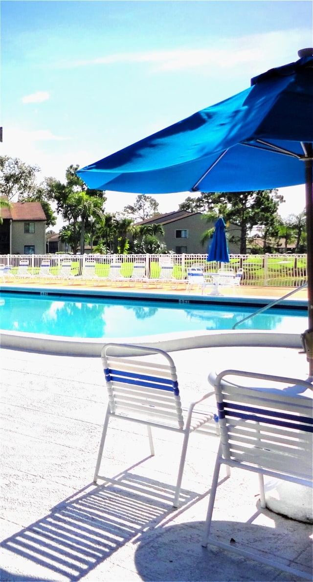 community pool with fence and a patio