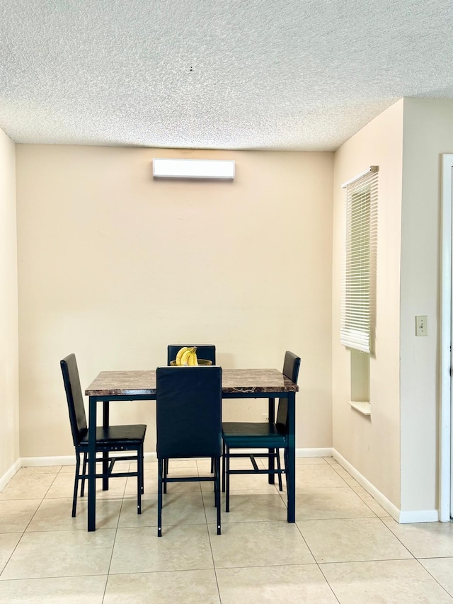dining room featuring a textured ceiling, baseboards, and light tile patterned flooring