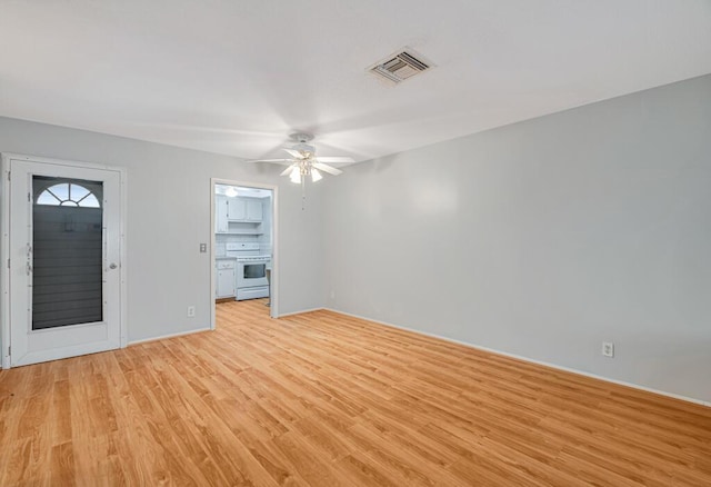 spare room featuring light wood finished floors, ceiling fan, and baseboards