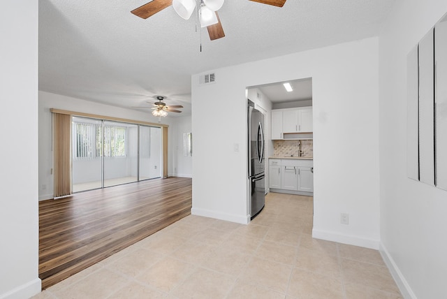 12416 Alternate A1A P7, Palm Beach Gardens, FL 33410 - unfurnished living room with a ceiling fan, a sink, light tile patterned floors, baseboards, and a textured ceiling