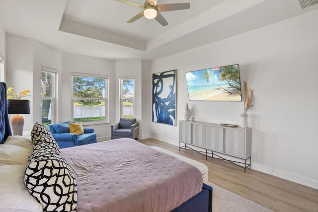 138 NW Magnolia Lakes Blvd, Port Saint Lucie, FL 34986 - bedroom featuring baseboards, wood finished floors, a tray ceiling, and a ceiling fan