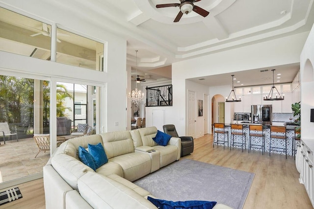 138 NW Magnolia Lakes Blvd, Port Saint Lucie, FL 34986 - living room featuring ceiling fan, a towering ceiling, arched walkways, a chandelier, and light wood finished floors