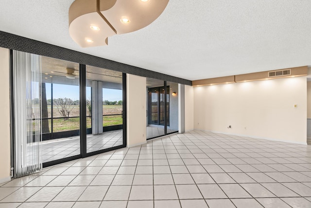 spare room featuring a textured ceiling, a ceiling fan, and light tile patterned floors