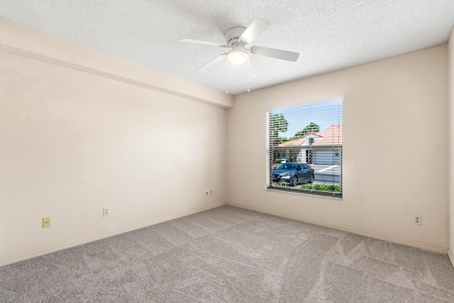 empty room with ceiling fan, light carpet, a textured ceiling, and baseboards