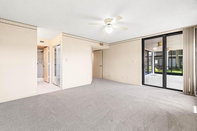 carpeted empty room with a ceiling fan and a wall of windows