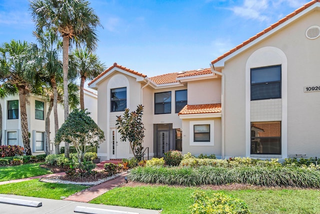 townhome / multi-family property with a tile roof and stucco siding