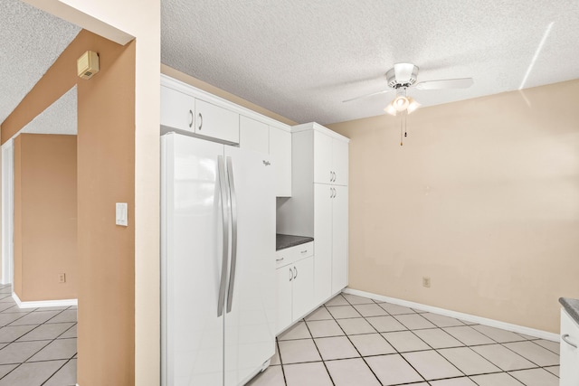 kitchen featuring freestanding refrigerator, a textured ceiling, ceiling fan, white cabinetry, and dark countertops