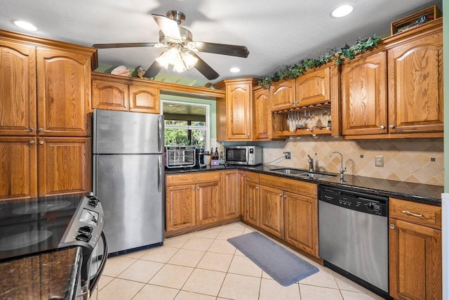 4901 129th Ave N, The Acreage, FL 33411 - kitchen featuring stainless steel appliances, brown cabinets, light tile patterned flooring, a sink, and tasteful backsplash