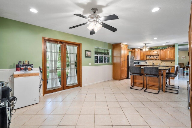 4901 129th Ave N, The Acreage, FL 33411 - kitchen featuring stainless steel appliances, wainscoting, ceiling fan, a kitchen breakfast bar, and french doors
