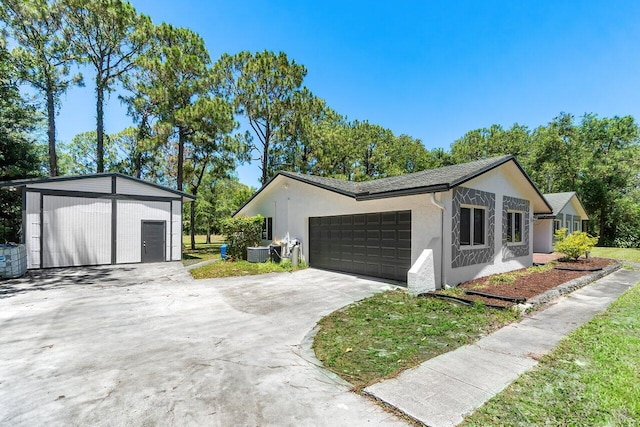 4901 129th Ave N, The Acreage, FL 33411 - view of front of property with central air condition unit, stucco siding, concrete driveway, an attached garage, and an outbuilding
