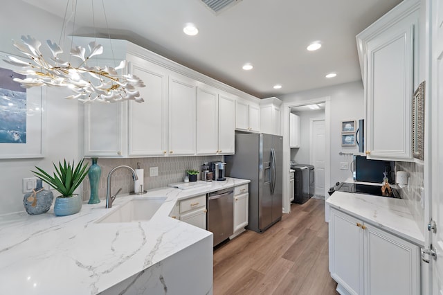 1310 S Jeaga Dr, Jupiter, FL 33458 - kitchen featuring a sink, separate washer and dryer, stainless steel appliances, white cabinets, and backsplash