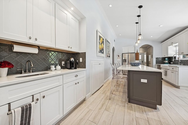 310 Almeria Rd, West Palm Beach, FL 33405 - kitchen with a sink, arched walkways, decorative backsplash, white cabinets, and recessed lighting
