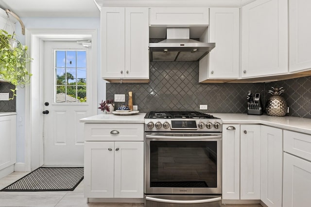 310 Almeria Rd, West Palm Beach, FL 33405 - kitchen featuring gas stove, wall chimney exhaust hood, light countertops, decorative backsplash, and white cabinets