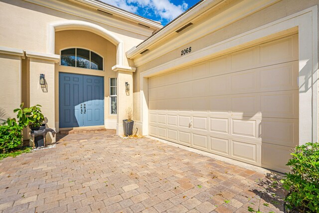 2068 Wightman Dr, Wellington, FL 33414 - view of exterior entry with decorative driveway, stucco siding, and a garage