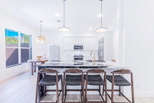 2068 Wightman Dr, Wellington, FL 33414 - kitchen with stainless steel appliances, a sink, light wood-style flooring, white cabinetry, and a kitchen breakfast bar