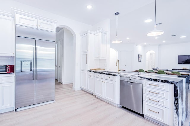 2068 Wightman Dr, Wellington, FL 33414 - kitchen featuring appliances with stainless steel finishes, arched walkways, white cabinets, decorative backsplash, and recessed lighting